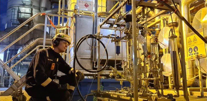 Technician kneeling beside chemical injection skid