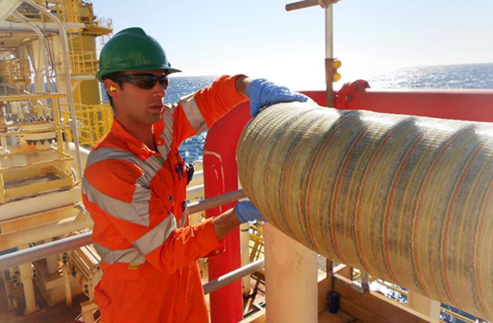 Technician applying composite wrap to pipe offshore in sunshine