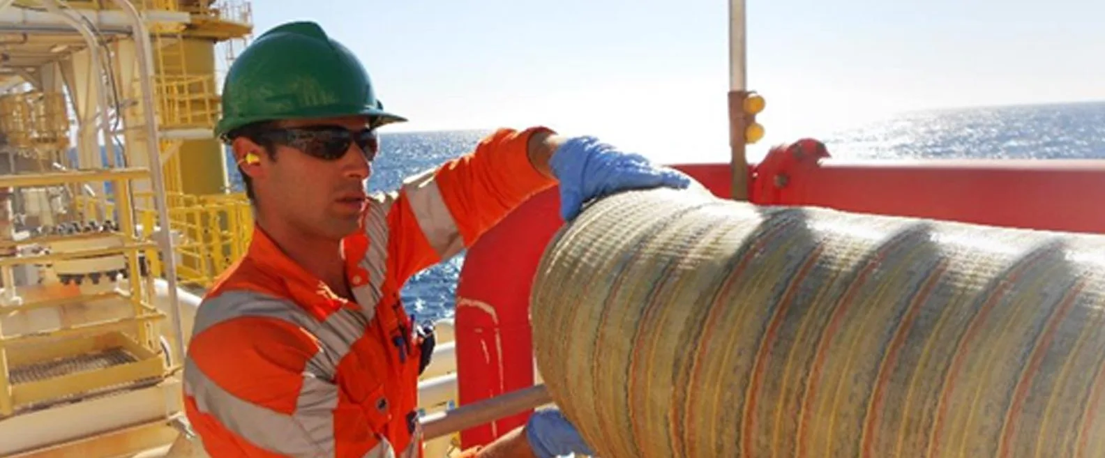 Technician applying composite wrap to pipe offshore in sunshine
